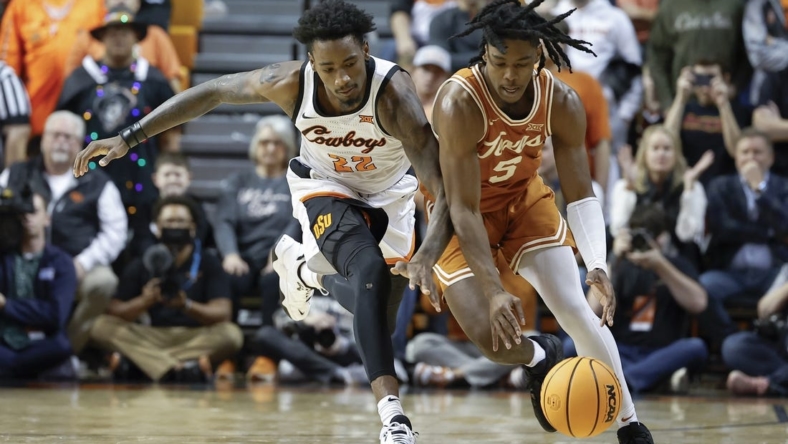 Jan 7, 2023; Stillwater, Oklahoma, USA; Oklahoma State Cowboys forward Kalib Boone (22) and Texas Longhorns guard Marcus Carr (5) reach for a loose ball during the first half at Gallagher-Iba Arena. Mandatory Credit: Alonzo Adams-USA TODAY Sports