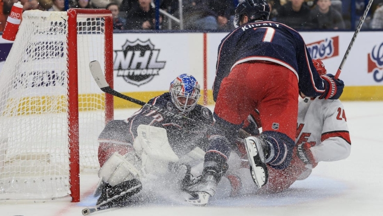 Jan 7, 2023; Columbus, Ohio, USA;  Columbus Blue Jackets goaltender Joonas Korpisalo (left) defends the net as Carolina Hurricanes center Seth Jarvis (right) is checked by Columbus Blue Jackets center Sean Kuraly in the third period at Nationwide Arena. Mandatory Credit: Aaron Doster-USA TODAY Sports