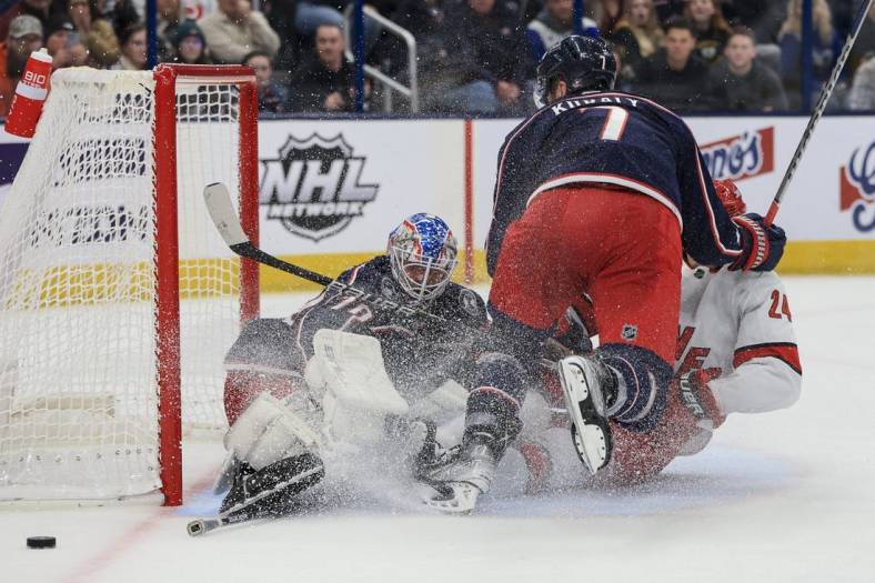 Jan 7, 2023; Columbus, Ohio, USA;  Columbus Blue Jackets goaltender Joonas Korpisalo (left) defends the net as Carolina Hurricanes center Seth Jarvis (right) is checked by Columbus Blue Jackets center Sean Kuraly in the third period at Nationwide Arena. Mandatory Credit: Aaron Doster-USA TODAY Sports