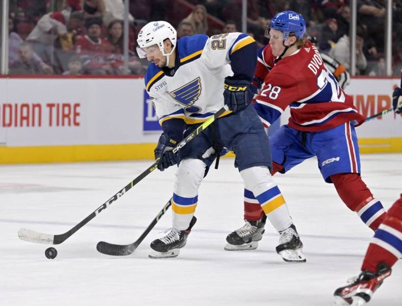 Jan 7, 2023; Montreal, Quebec, CAN; St. Louis Blues forward Jordan Kyrou (25) plays the puck against Montreal Canadiens forward Christian Dvorak (28) during the first period at the Bell Centre. Mandatory Credit: Eric Bolte-USA TODAY Sports