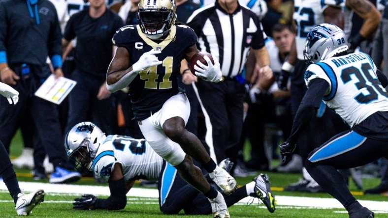 Jan 8, 2023; New Orleans, Louisiana, USA;  New Orleans Saints running back Alvin Kamara (41) runs against Carolina Panthers cornerback Myles Hartsfield (38) and safety Xavier Woods (25) during the first half at Caesars Superdome. Mandatory Credit: Stephen Lew-USA TODAY Sports
