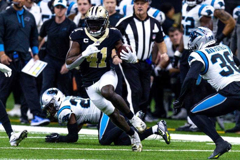 Jan 8, 2023; New Orleans, Louisiana, USA;  New Orleans Saints running back Alvin Kamara (41) runs against Carolina Panthers cornerback Myles Hartsfield (38) and safety Xavier Woods (25) during the first half at Caesars Superdome. Mandatory Credit: Stephen Lew-USA TODAY Sports