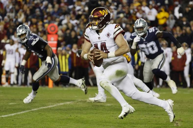 Jan 8, 2023; Landover, Maryland, USA; Washington Commanders quarterback Sam Howell (14) runs with the ball as Dallas Cowboys defensive end DeMarcus Lawrence (90) chases during the second quarter at FedExField. Mandatory Credit: Geoff Burke-USA TODAY Sports