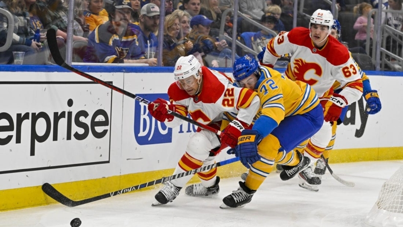 Jan 10, 2023; St. Louis, Missouri, USA;  Calgary Flames center Trevor Lewis (22) and St. Louis Blues defenseman Justin Faulk (72) battle for the puck during the first period at Enterprise Center. Mandatory Credit: Jeff Curry-USA TODAY Sports