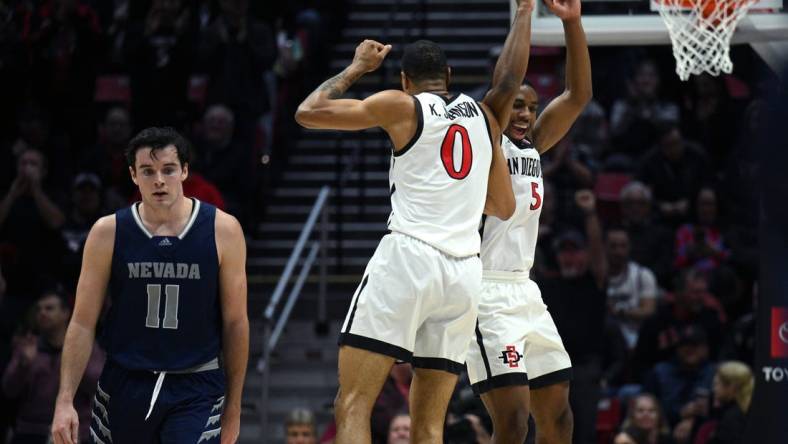 Jan 10, 2023; San Diego, California, USA; San Diego State Aztecs forward Keshad Johnson (0) and guard Lamont Butler (5) celebrate as Nevada Wolf Pack forward Nick Davidson (11) looks on during the first half at Viejas Arena. Mandatory Credit: Orlando Ramirez-USA TODAY Sports