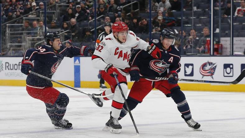 Jan 12, 2023; Columbus, Ohio, USA; Carolina Hurricanes center Jesperi Kotkaniemi (82) avoids then check from Columbus Blue Jackets center Gustav Nyquist (14) during the first period at Nationwide Arena. Mandatory Credit: Russell LaBounty-USA TODAY Sports