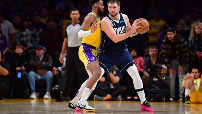 Jan 12, 2023; Los Angeles, California, USA; Dallas Mavericks guard Luka Doncic (77) moves the ball against Los Angeles Lakers forward Troy Brown Jr. (7) during overtime at Crypto.com Arena. Mandatory Credit: Gary A. Vasquez-USA TODAY Sports