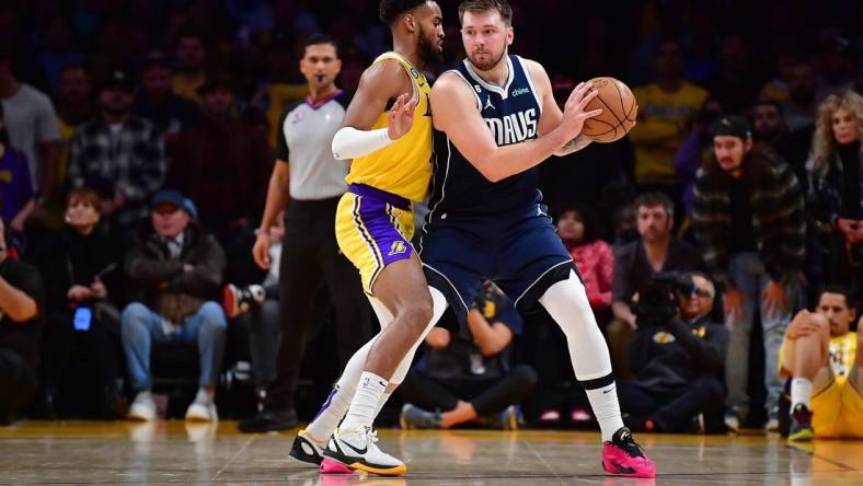 Jan 12, 2023; Los Angeles, California, USA; Dallas Mavericks guard Luka Doncic (77) moves the ball against Los Angeles Lakers forward Troy Brown Jr. (7) during overtime at Crypto.com Arena. Mandatory Credit: Gary A. Vasquez-USA TODAY Sports
