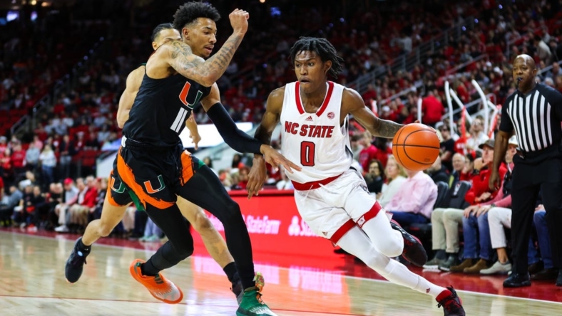 Jan 14, 2023; Raleigh, North Carolina, USA; North Carolina State Wolfpack guard Terquavion Smith (0) runs with the ball guarded by Miami Hurricanes guard Jordan Miller (11)  during the first half against Miami Hurricanes at PNC Arena. Mandatory Credit: Jaylynn Nash-USA TODAY Sports