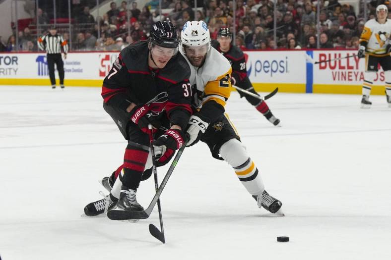 Jan 14, 2023; Raleigh, North Carolina, USA;  Carolina Hurricanes right wing Andrei Svechnikov (37) and Pittsburgh Penguins defenseman Ty Smith (24) battle over the puck during the first period at PNC Arena. Mandatory Credit: James Guillory-USA TODAY Sports