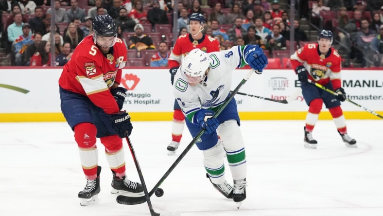 Jan 14, 2023; Sunrise, Florida, USA; Vancouver Canucks right wing Conor Garland (8) and Florida Panthers defenseman Aaron Ekblad (5) battle for the puck during the first period at FLA Live Arena. Mandatory Credit: Jasen Vinlove-USA TODAY Sports