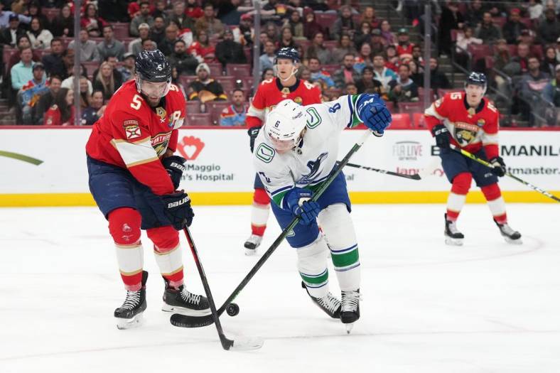 Jan 14, 2023; Sunrise, Florida, USA; Vancouver Canucks right wing Conor Garland (8) and Florida Panthers defenseman Aaron Ekblad (5) battle for the puck during the first period at FLA Live Arena. Mandatory Credit: Jasen Vinlove-USA TODAY Sports