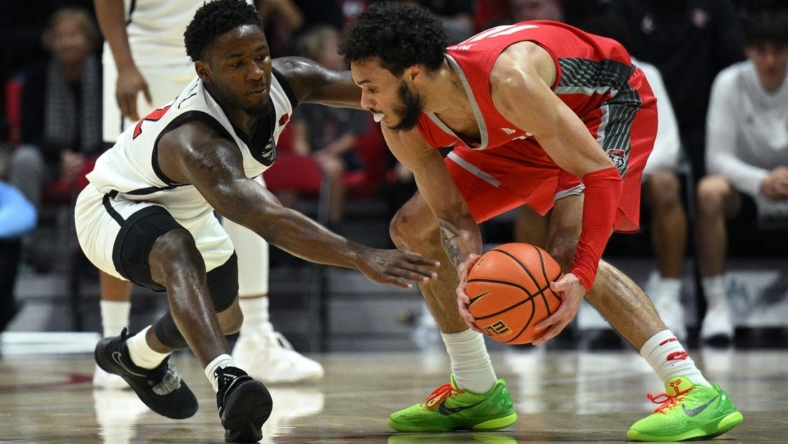 Jan 14, 2023; San Diego, California, USA; New Mexico Lobos guard Jaelen House (10) controls the ball while defended by San Diego State Aztecs guard Darrion Trammell (12) during the first half at Viejas Arena. Mandatory Credit: Orlando Ramirez-USA TODAY Sports