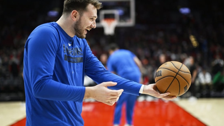Jan 14, 2023; Portland, Oregon, USA; Dallas Mavericks guard Luka Doncic (77) playfully hands the ball to an assistant coach before a game against the Portland Trail Blazers at Moda Center. Mandatory Credit: Troy Wayrynen-USA TODAY Sports
