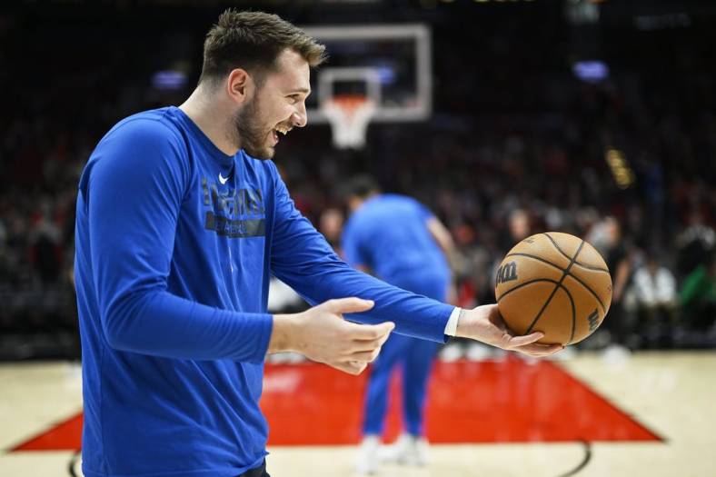 Jan 14, 2023; Portland, Oregon, USA; Dallas Mavericks guard Luka Doncic (77) playfully hands the ball to an assistant coach before a game against the Portland Trail Blazers at Moda Center. Mandatory Credit: Troy Wayrynen-USA TODAY Sports
