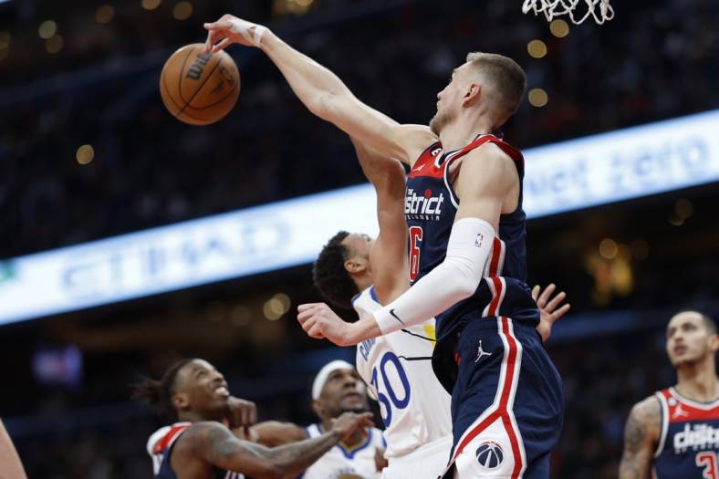 Jan 16, 2023; Washington, District of Columbia, USA; Washington Wizards center Kristaps Porzingis (6) blocks the shot of Golden State Warriors guard Stephen Curry (30) in the first quarter at Capital One Arena. Mandatory Credit: Geoff Burke-USA TODAY Sports