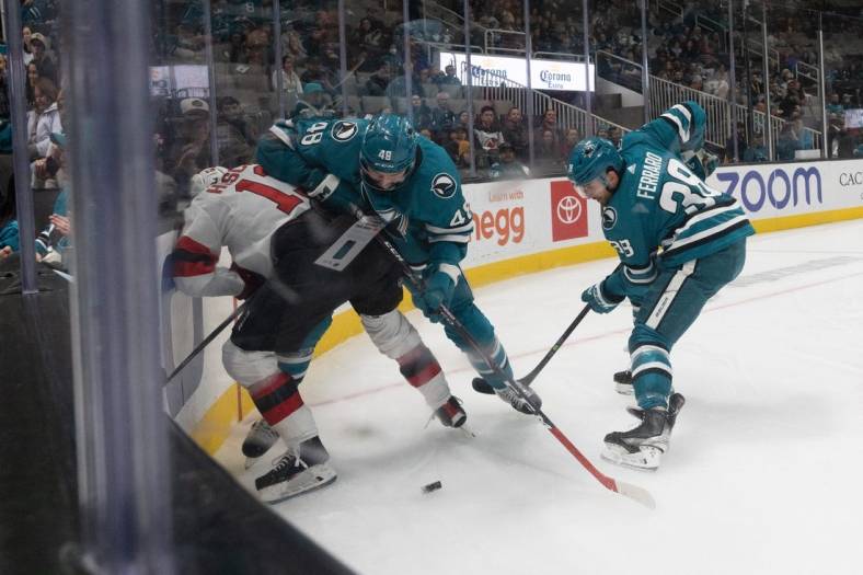 Jan 16, 2023; San Jose, California, USA;  New Jersey Devils center Nico Hischier (13) is shoved into the boards by San Jose Sharks center Tomas Hertl (48) whileSan Jose Sharks defenseman Mario Ferraro (38) reaches for the puck during the first period at SAP Center at San Jose. Mandatory Credit: Stan Szeto-USA TODAY Sports