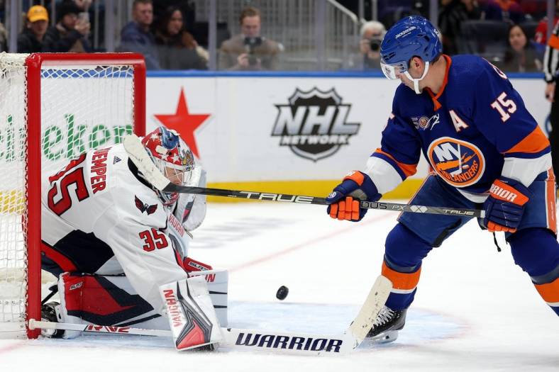 Jan 16, 2023; Elmont, New York, USA; Washington Capitals goaltender Darcy Kuemper (35) and New York Islanders right wing Cal Clutterbuck (15) play the puck during the second period at UBS Arena. Mandatory Credit: Brad Penner-USA TODAY Sports