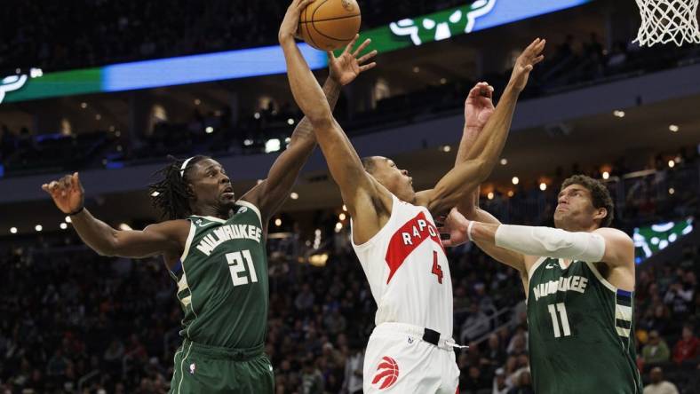 Jan 17, 2023; Milwaukee, Wisconsin, USA;  Toronto Raptors forward Scottie Barnes (4) shoots between Milwaukee Bucks guard Jrue Holiday (21) and center Brook Lopez (11) during the third quarter at Fiserv Forum. Mandatory Credit: Jeff Hanisch-USA TODAY Sports