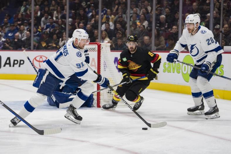 Jan 18, 2023; Vancouver, British Columbia, CAN; Vancouver Canucks forward Conor Garland (8) and Tampa Bay Lightning defenseman Ian Cole (28) watch as forward Steven Stamkos (91) handles the puck in the first period at Rogers Arena. Mandatory Credit: Bob Frid-USA TODAY Sports