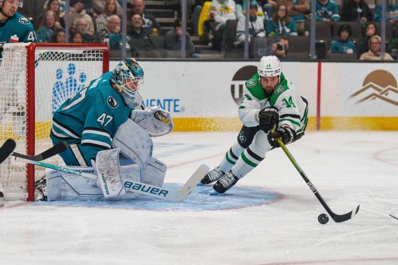 Jan 18, 2023; San Jose, California, USA; Dallas Stars left wing Jamie Benn (14) attempt to control the puck in front of San Jose Sharks goaltender James Reimer (47) during the first period at SAP Center at San Jose. Mandatory Credit: Neville E. Guard-USA TODAY Sports