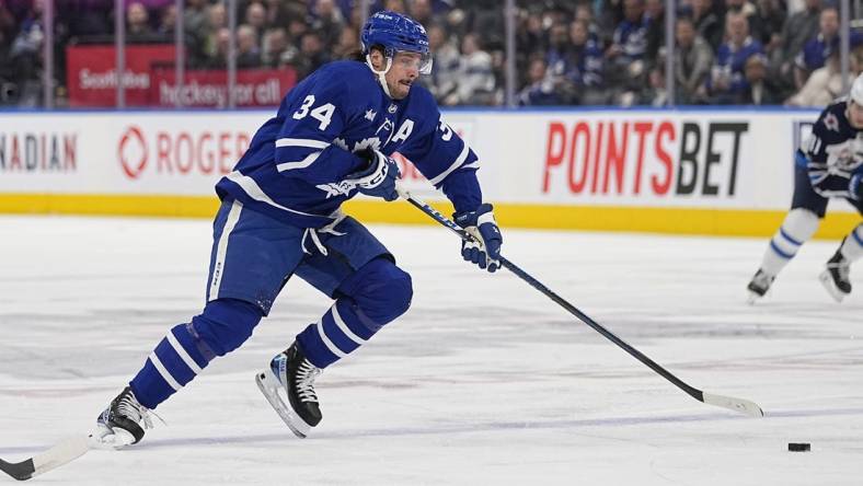 Jan 19, 2023; Toronto, Ontario, CAN; Toronto Maple Leafs forward Auston Matthews (34) tries to get control of a puck against the Winnipeg Jets during the first period at Scotiabank Arena. Mandatory Credit: John E. Sokolowski-USA TODAY Sports