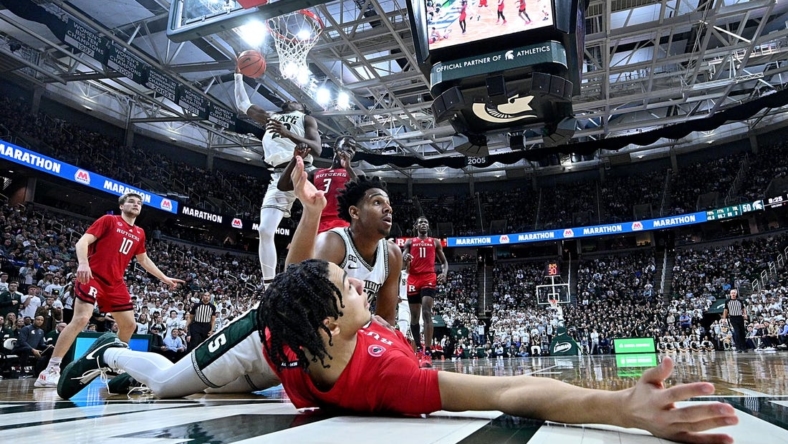 Jan 19, 2023; East Lansing, Michigan, USA;  In the foreground, Rutgers Scarlet Knights guard Derek Simpson (0) and Michigan State Spartans guard A.J. Hoggard (11) wait for the verdict from the referee after a collision under the basket in the second half at Jack Breslin Student Events Center. Rutgers Scarlet Knights guard Derek Simpson (0) was called on a blocking foul. Mandatory Credit: Dale Young-USA TODAY Sports