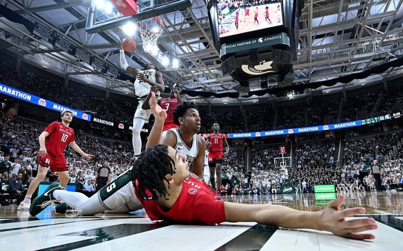 Jan 19, 2023; East Lansing, Michigan, USA;  In the foreground, Rutgers Scarlet Knights guard Derek Simpson (0) and Michigan State Spartans guard A.J. Hoggard (11) wait for the verdict from the referee after a collision under the basket in the second half at Jack Breslin Student Events Center. Rutgers Scarlet Knights guard Derek Simpson (0) was called on a blocking foul. Mandatory Credit: Dale Young-USA TODAY Sports