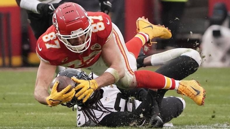 Jan 21, 2023; Kansas City, Missouri, USA; Kansas City Chiefs tight end Travis Kelce (87) moves the ball ahead of Jacksonville Jaguars safety Rayshawn Jenkins (2) during the first half in the AFC divisional round game at GEHA Field at Arrowhead Stadium. Mandatory Credit: Denny Medley-USA TODAY Sports