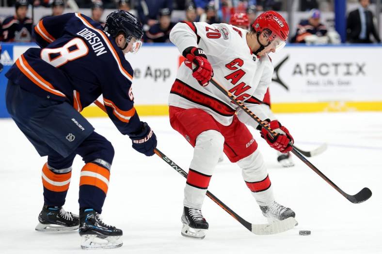 Jan 21, 2023; Elmont, New York, USA; Carolina Hurricanes center Sebastian Aho (20) and New York Islanders defenseman Noah Dobson (8) fight for the puck during the first period at UBS Arena. Mandatory Credit: Brad Penner-USA TODAY Sports