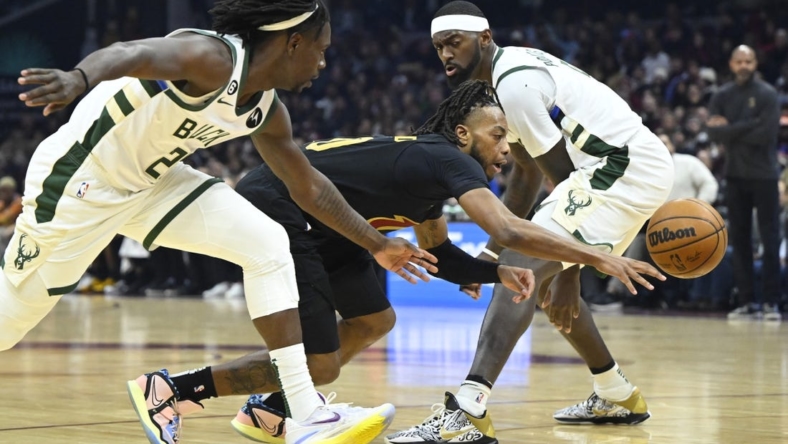 Jan 21, 2023; Cleveland, Ohio, USA; Cleveland Cavaliers guard Darius Garland (10) dribbles between Milwaukee Bucks guard Jrue Holiday (21) and forward Bobby Portis (9) in the second quarter at Rocket Mortgage FieldHouse. Mandatory Credit: David Richard-USA TODAY Sports