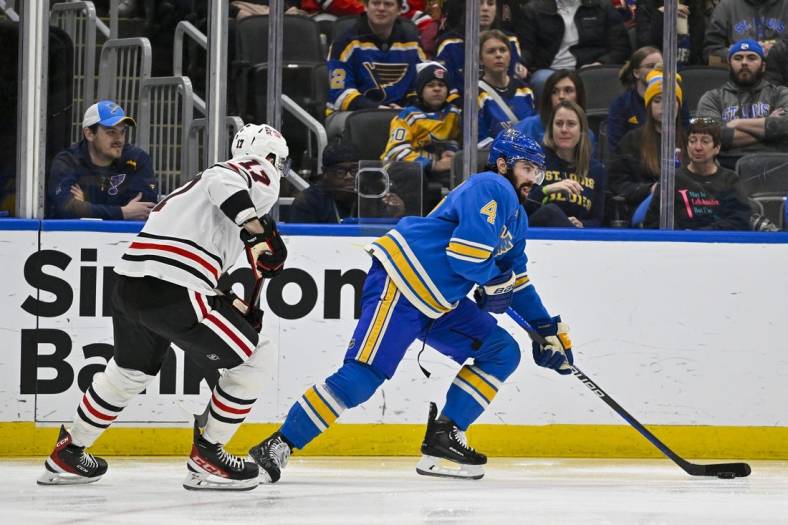 Jan 21, 2023; St. Louis, Missouri, USA;  St. Louis Blues defenseman Nick Leddy (4) controls the puck as Chicago Blackhawks center Jason Dickinson (17) defends during the first period at Enterprise Center. Mandatory Credit: Jeff Curry-USA TODAY Sports