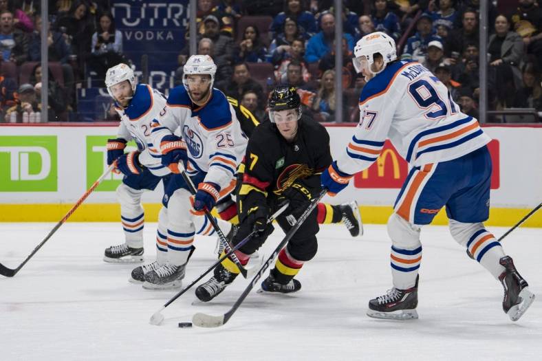Jan 21, 2023; Vancouver, British Columbia, CAN; Edmonton Oilers defenseman Darnell Nurse (25) and forward Connor McDavid (97) and Vancouver Canucks forward William Lockwood (7) battle for the loose puck in the first period at Rogers Arena. Mandatory Credit: Bob Frid-USA TODAY Sports