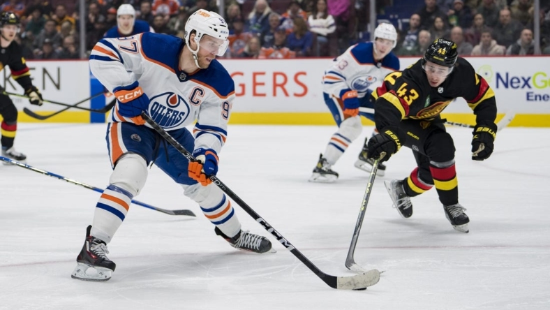 Jan 21, 2023; Vancouver, British Columbia, CAN; Edmonton Oilers forward Connor McDavid (97) passes around Vancouver Canucks defenseman Quinn Hughes (43) in the second period at Rogers Arena. Mandatory Credit: Bob Frid-USA TODAY Sports