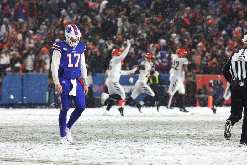 Bills quarterback Josh Allen walks off the field after throwing an interception late in the fourth quarter at Highmark Stadium in Orchard Park on Jan. 22  In the background the Cincinnati Bengals players celebrate.

Ty 012223 Dejected Josh Allen After Fourth Quarter Interception