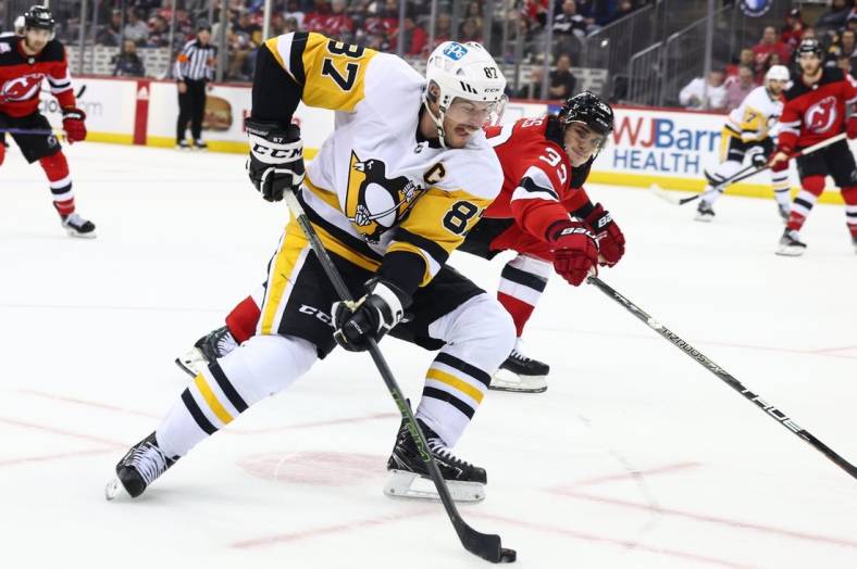 Jan 22, 2023; Newark, New Jersey, USA; Pittsburgh Penguins center Sidney Crosby (87) skates with the puck while being defended by New Jersey Devils defenseman Ryan Graves (33) during the third period at Prudential Center. Mandatory Credit: Ed Mulholland-USA TODAY Sports