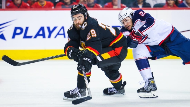 Jan 23, 2023; Calgary, Alberta, CAN; Calgary Flames center Dillon Dube (29) and Columbus Blue Jackets defenseman Andrew Peeke (2) battle for the puck during the second period at Scotiabank Saddledome. Mandatory Credit: Sergei Belski-USA TODAY Sports