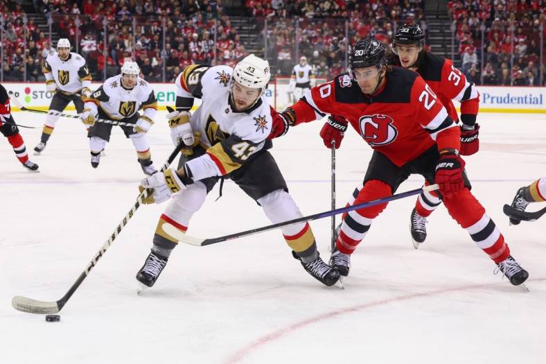 Jan 24, 2023; Newark, New Jersey, USA; Vegas Golden Knights center Paul Cotter (43) plays the puck while being defended by New Jersey Devils center Michael McLeod (20) during the first period at Prudential Center. Mandatory Credit: Ed Mulholland-USA TODAY Sports