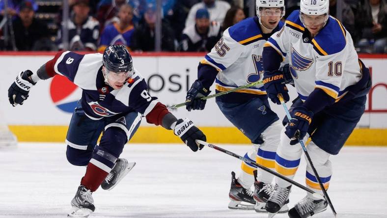 Jan 28, 2023; Denver, Colorado, USA; St. Louis Blues center Brayden Schenn (10) controls the puck under pressure from Colorado Avalanche center Evan Rodrigues (9) as center Jordan Kyrou (25) looks on in the first period at Ball Arena. Mandatory Credit: Isaiah J. Downing-USA TODAY Sports
