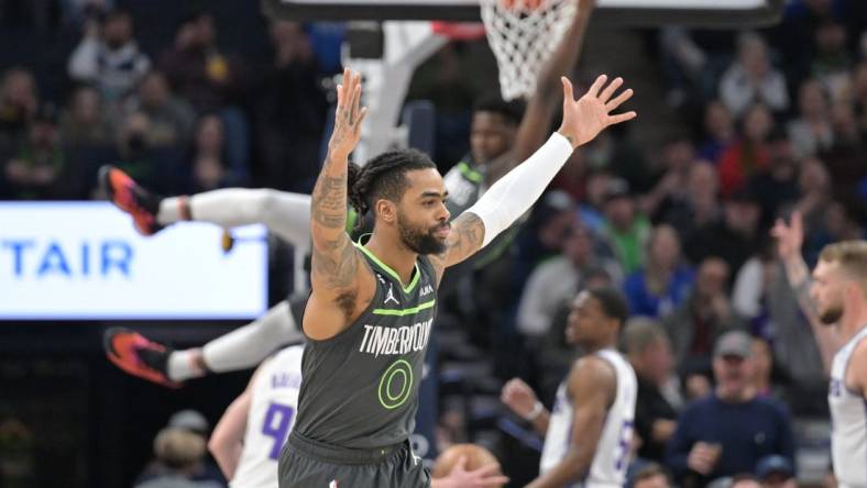 Jan 28, 2023; Minneapolis, Minnesota, USA; Minnesota Timberwolves guard D'Angelo Russell (0) reacts as guard Anthony Edwards (1) hangs from the rim against the Sacramento Kings during the first quarter at Target Center. Mandatory Credit: Jeffrey Becker-USA TODAY Sports