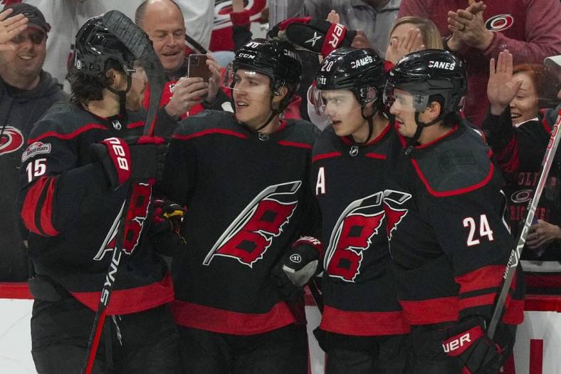 Jan 29, 2023; Raleigh, North Carolina, USA;  Carolina Hurricanes center Sebastian Aho (20) is congratulated by  center Seth Jarvis (24) left wing Teuvo Teravainen (86) and defenseman Dylan Coghlan (15) after his goal against the Boston Bruins during the first period at PNC Arena. Mandatory Credit: James Guillory-USA TODAY Sports