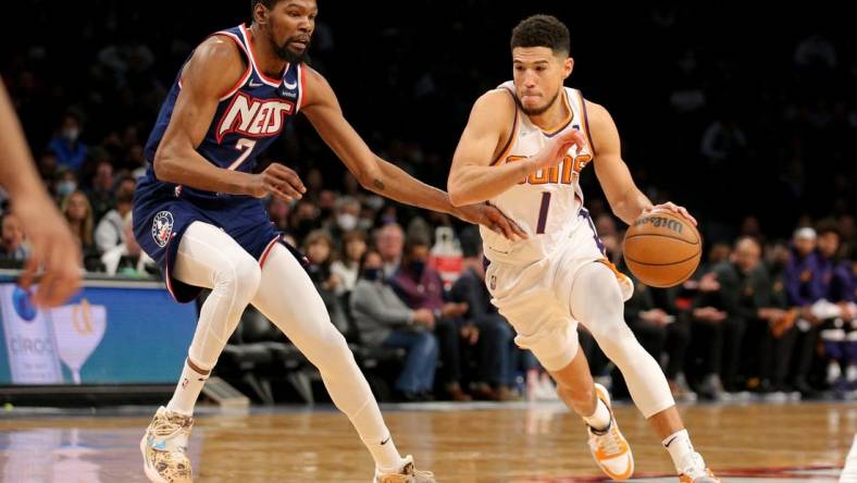 Nov 27, 2021; Brooklyn, New York, USA; Phoenix Suns guard Devin Booker (1) drives with the ball around Brooklyn Nets forward Kevin Durant (7) during the first quarter at Barclays Center. Mandatory Credit: Brad Penner-USA TODAY Sports