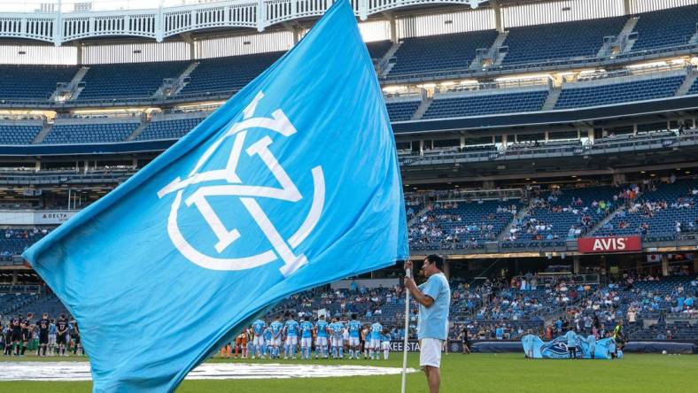 Jul 23, 2022; New York, New York, USA; A fan holds a NYCFC flag on the pitch before a match between New York City FC and Inter Miami CF at Yankee Stadium. Mandatory Credit: Vincent Carchietta-USA TODAY Sports