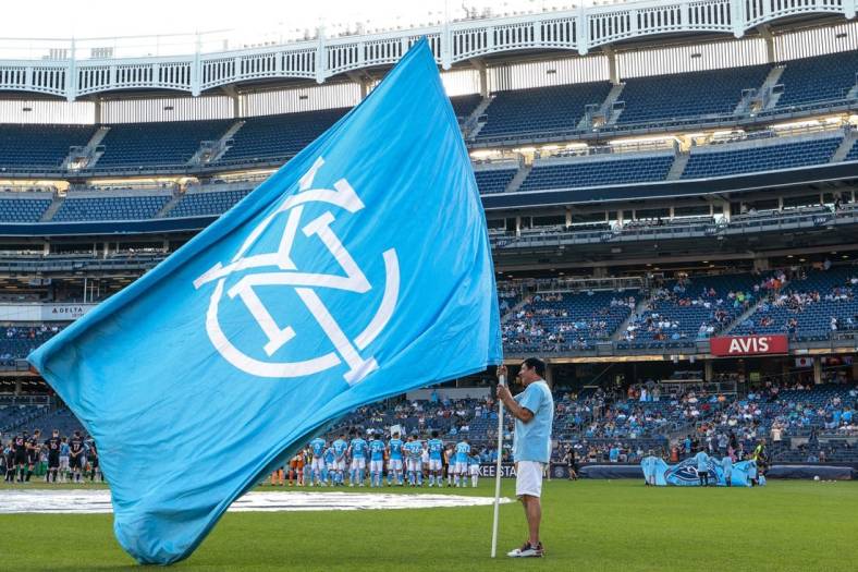 Jul 23, 2022; New York, New York, USA; A fan holds a NYCFC flag on the pitch before a match between New York City FC and Inter Miami CF at Yankee Stadium. Mandatory Credit: Vincent Carchietta-USA TODAY Sports
