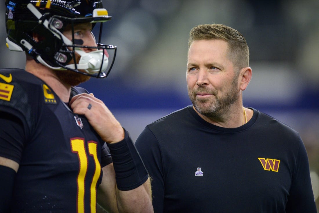 Oct 2, 2022; Arlington, Texas, USA; Washington Commanders quarterback Carson Wentz (left) talks with offensive coordinator Scott Turner (right) before the game between the Dallas Cowboys and the Washington Commanders at AT&T Stadium. Mandatory Credit: Jerome Miron-USA TODAY Sports