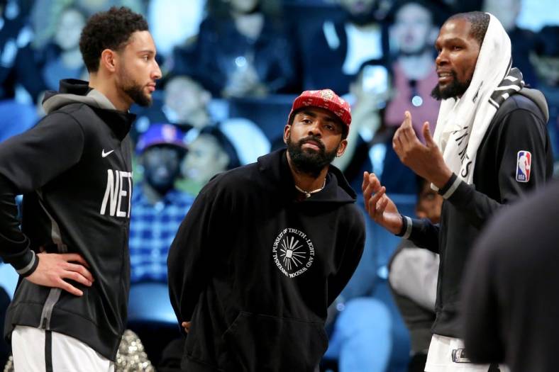 Oct 6, 2022; Brooklyn, New York, USA; Brooklyn Nets guard Kyrie Irving (center) talks to guard Ben Simmons (left) and forward Kevin Durant (7) during the fourth quarter against the Miami Heat at Barclays Center. Mandatory Credit: Brad Penner-USA TODAY Sports