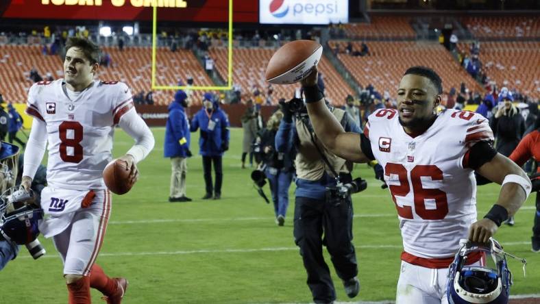 Dec 18, 2022; Landover, Maryland, USA; New York Giants quarterback Daniel Jones (8) and Giants running back Saquon Barkley (26) celebrate while leaving the field after their game against the Washington Commanders at FedExField. Mandatory Credit: Geoff Burke-USA TODAY Sports