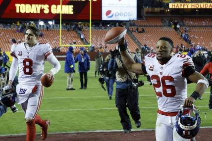 Dec 18, 2022; Landover, Maryland, USA; New York Giants quarterback Daniel Jones (8) and Giants running back Saquon Barkley (26) celebrate while leaving the field after their game against the Washington Commanders at FedExField. Mandatory Credit: Geoff Burke-USA TODAY Sports