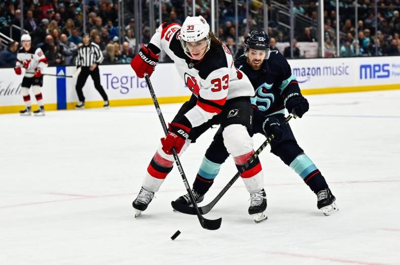 Jan 19, 2023; Seattle, Washington, USA; New Jersey Devils defenseman Ryan Graves (33) protects the puck from Seattle Kraken right wing Oliver Bjorkstrand (22) during the third period at Climate Pledge Arena. Seattle defeated New Jersey 4-3. Mandatory Credit: Steven Bisig-USA TODAY Sports