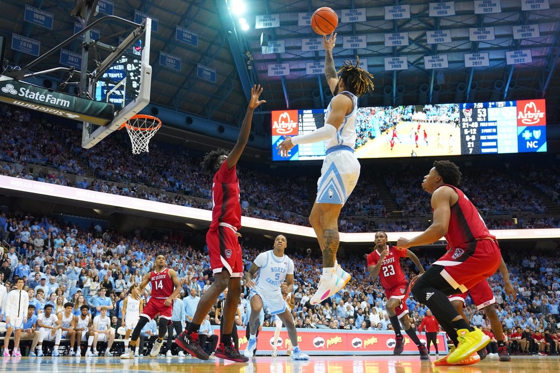 Jan 21, 2023; Chapel Hill, North Carolina, USA; North Carolina Tar Heels guard R.J. Davis (4) shoots as North Carolina State Wolfpack forward Ebenezer Dowuona (21) and guard LJ Thomas (4) defend in the second half at Dean E. Smith Center. Mandatory Credit: Bob Donnan-USA TODAY Sports